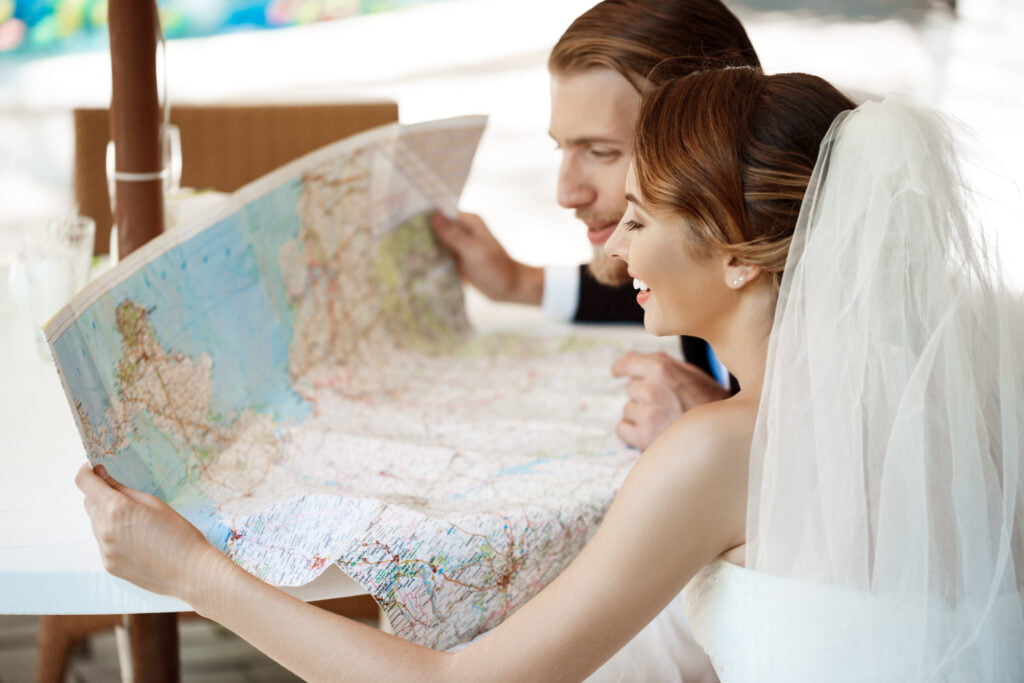 jovens recem casados lindos sorrindo escolhendo a viagem de lua de mel olhando para o mapa