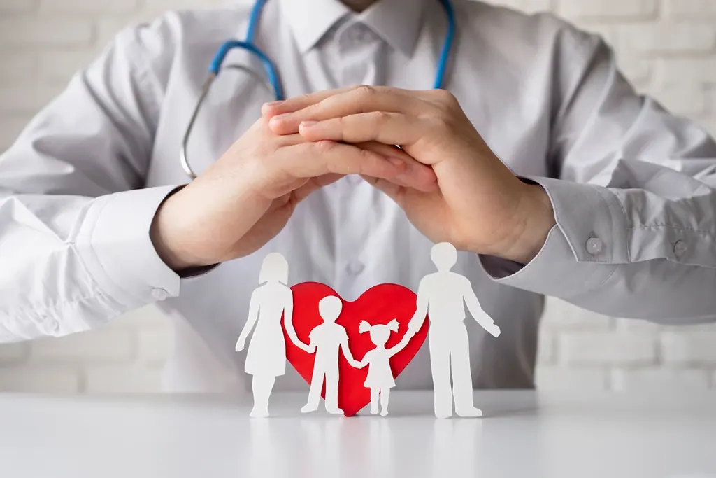 Mãos de um médico protegendo uma família de papel com um coração vermelho