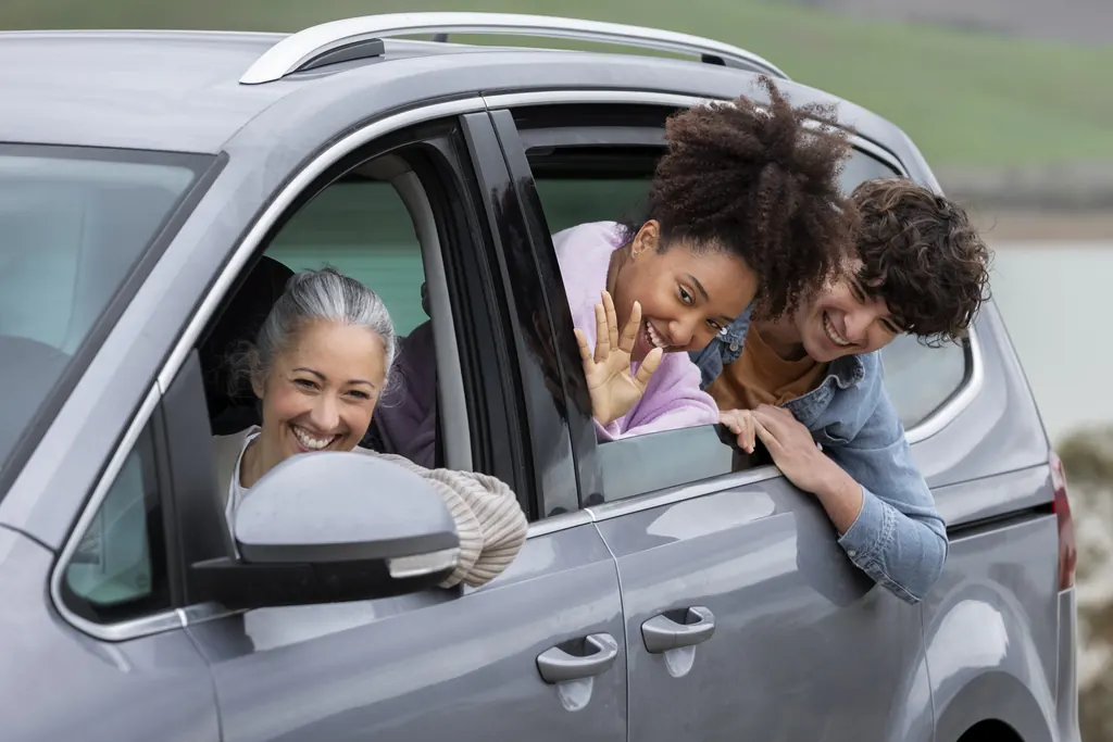 Família sorrindo nas janelas do carro durante uma viagem