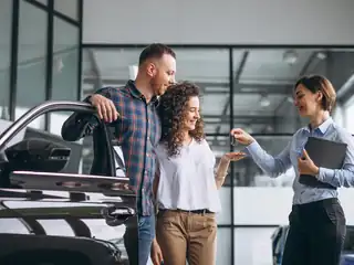 Casal recebendo a chave de um carro em uma concessionária